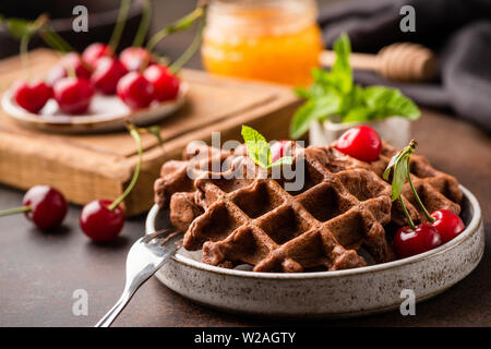 Gaufres au chocolat avec cerises et miel sur une assiette. Gaufres de blé entier, petit-déjeuner sain ou dessert concept Banque D'Images