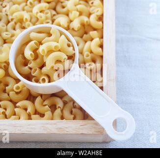 La nourriture et la cuisine, vue de dessus et non cuits ou secs Macaroni Coude Gomiti pâtes dans une tasse à mesurer en plastique. Banque D'Images