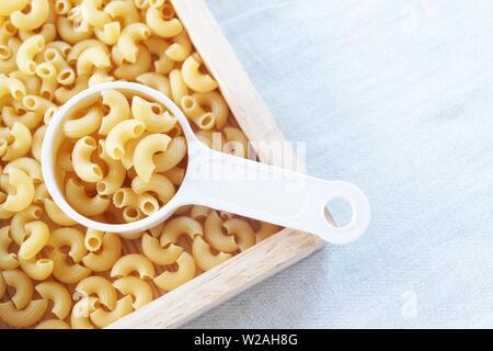 La nourriture et la cuisine, vue de dessus et non cuits ou secs Macaroni Coude Gomiti pâtes dans une tasse à mesurer en plastique. Banque D'Images