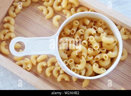 La nourriture et la cuisine, vue de dessus et non cuits ou secs Macaroni Coude Gomiti pâtes dans une tasse à mesurer en plastique. Banque D'Images