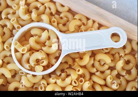 La nourriture et la cuisine, vue de dessus et non cuits ou secs Macaroni Coude Gomiti pâtes dans une tasse à mesurer en plastique. Banque D'Images