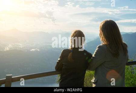 Femme et sa fille appréciant le lever du soleil du haut d'une montagne. Banque D'Images