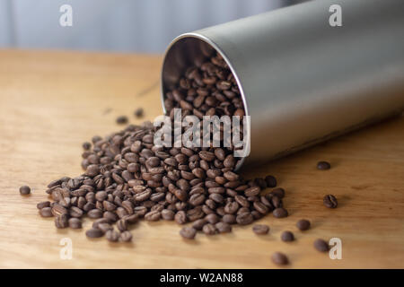 Café en grains s'échappant d'un récipient en métal tubulaire Banque D'Images