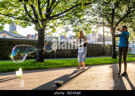 Pays de Galles Aberystwyth UK, Dimanche 07 Juillet 2019 Royaume-Uni Météo : une famille dans le parc à Aberystwyth et s'amuser en jouant avec bulle de savon géante dans le soleil du soir à la fin de l'été dans l'ouest du pays de Galles. Crédit photo : Keith Morris/Alamy Live News Banque D'Images