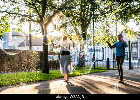 Pays de Galles Aberystwyth UK, Dimanche 07 Juillet 2019 Royaume-Uni Météo : une famille dans le parc à Aberystwyth et s'amuser en jouant avec bulle de savon géante dans le soleil du soir à la fin de l'été dans l'ouest du pays de Galles. Crédit photo : Keith Morris/Alamy Live News Banque D'Images