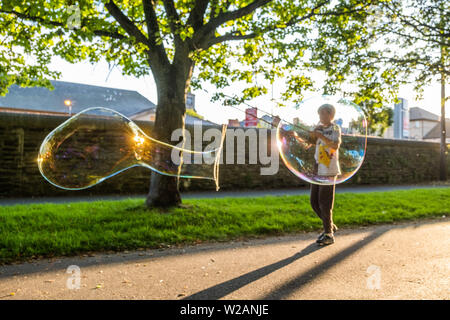 Pays de Galles Aberystwyth UK, Dimanche 07 Juillet 2019 Royaume-Uni Météo : une famille dans le parc à Aberystwyth et s'amuser en jouant avec bulle de savon géante dans le soleil du soir à la fin de l'été dans l'ouest du pays de Galles. Crédit photo : Keith Morris/Alamy Live News Banque D'Images