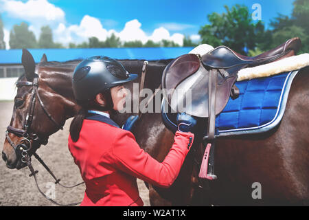 Fille ajuste jockey sur son cheval de selle de prendre part à des courses de chevaux Banque D'Images