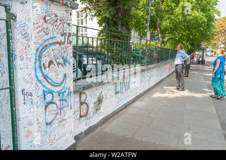 Londres, ANGLETERRE - 17 juillet 2013 ; Couple de touristes sur l'extérieur d'Abbey Road studios à la plus célèbre mur couvert grafitti. Banque D'Images