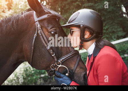 Une jeune fille parler et s'embrasser son cheval. Elle aime les animaux et joyeusement passe son temps dans leur environnement. Banque D'Images