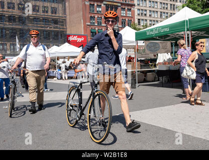 Deux hommes, possiblement liés à pied leurs vélos identiques grâce à l'Union Square Green Market à Manhattan, New York City Banque D'Images