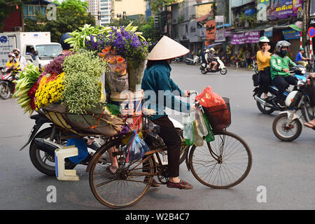 Hanoi / Vietnam - 31 mars 2019 : une vietnamienne vend des fleurs et utilise son vélo pour leur transport, dans la zone vieux quartier de Hanoi Banque D'Images