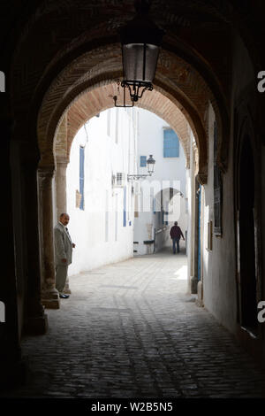 Un vieux homme tunisien permanent, sous un plafond voûté dans une ruelle piétonne dans la Médina de Tunis, Tunisie. Banque D'Images