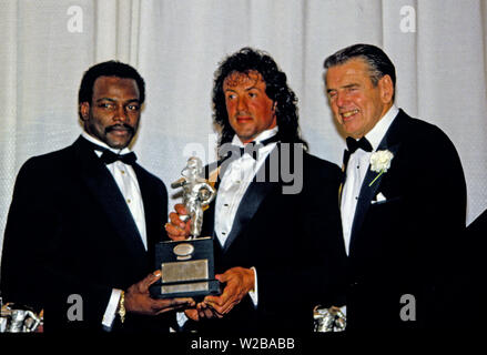 23 janvier 1988 - Washington, District of Columbia, États-Unis - Chicago Bears Walter Payton running back (34), à gauche, et l'actrice, scénariste, producteur et Sylvester Stallone, centre, maintenez la Timmie Award, tenez le trophée à être présenté à la défensive s'attaquer le Tchad Hennings de l'United States Air Force Academy, le Collège 1987 Poseur de l'année. Le prix est présenté dans le mémoire de Knute Rockne par le Washington, DC Touchdown Club à Washington, DC Le 23 janvier 1988. À la droite est l'ancien entraîneur-chef Redskins de Washington George Allen (crédit Image : © Arnie Sachs/CNP via ZUM Banque D'Images