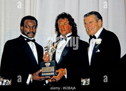 Running back Chicago Bears Walter Payton (34), à gauche, et l'actrice, scénariste, producteur et Sylvester Stallone, centre, maintenez la Timmie Award, tenez le trophée à être présenté à la défensive s'attaquer le Tchad Hennings de l'United States Air Force Academy, le Collège 1987 Poseur de l'année. Le prix est présenté dans le mémoire de Knute Rockne par le Washington, DC Touchdown Club à Washington, DC Le 23 janvier 1988. À la droite est l'ancien entraîneur-chef Redskins de Washington George Allen.Credit : Arnie Sachs/CNP | conditions dans le monde entier Banque D'Images