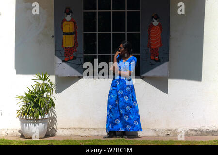 Une belle jeune femme indienne modèle dans une robe bleue s'amusant et posant devant la fenêtre d'un café avec des Chinois d'art graffiti sur le mur. Banque D'Images