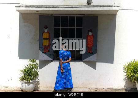 Une belle jeune femme indienne modèle dans une robe bleue s'amusant et posant devant la fenêtre d'un café avec des Chinois d'art graffiti sur le mur. Banque D'Images