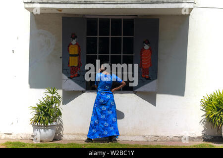 Une belle jeune femme indienne modèle dans une robe bleue s'amusant et posant devant la fenêtre d'un café avec des Chinois d'art graffiti sur le mur. Banque D'Images