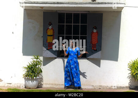 Une belle jeune femme indienne modèle dans une robe bleue s'amusant et posant devant la fenêtre d'un café avec des Chinois d'art graffiti sur le mur. Banque D'Images