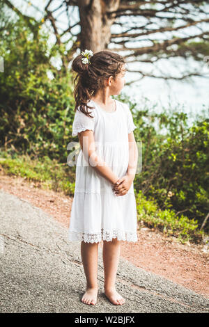 Belle jeune fille aux pieds nus en robe blanche, debout près de la montagne. Banque D'Images