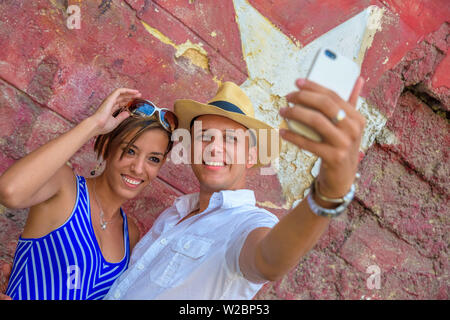 Cuba, La Havane, un couple de touristes en face de peinture murale selfies Banque D'Images