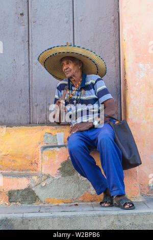 Cuba, Camaguey, la province de Camaguey, la Plaza San Juan de Dios, Ederly man sitting on steps fumeurs de cigare cubain Banque D'Images