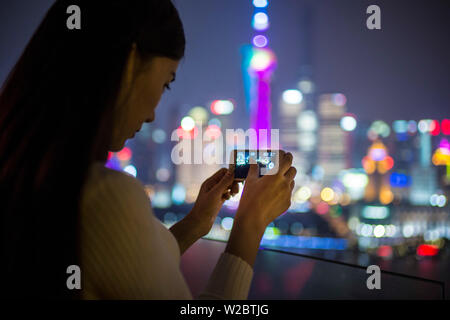 Woman taking photos avec le smartphone de l'horizon infornt de Pudong, Shanghai, Chine (MR) Banque D'Images