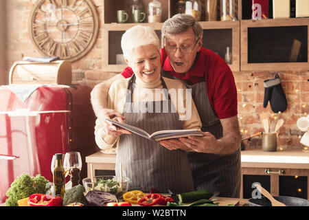 Senior couple preparing déjeuner avec livre de recettes Banque D'Images