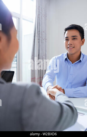 Cheerful young Vietnamese man shaking hand de HR manager après l'entretien d'embauche Banque D'Images
