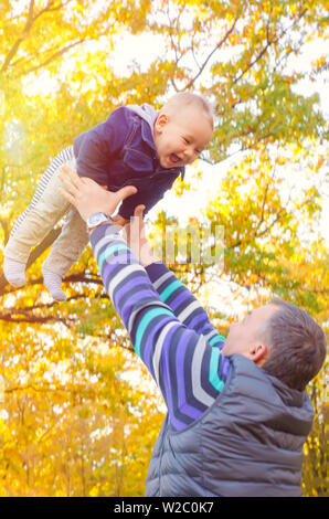 Le père et le bébé jouant à l'autumn park Banque D'Images