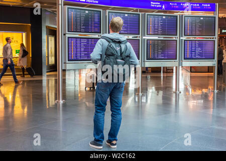 L'homme regardant un calendrier dans un aéroport Banque D'Images