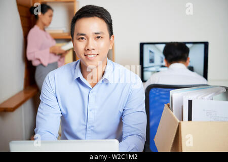 Portrait of handsome smiling young Vietnamese woman sa table en compagnie de bureau Banque D'Images