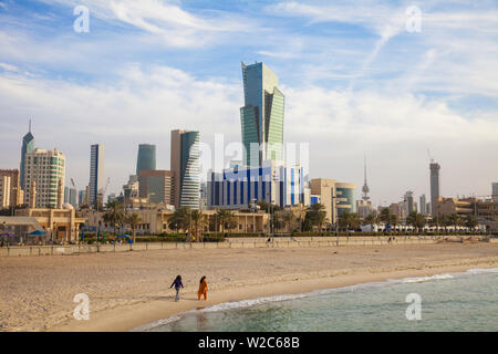 Le Koweït, Koweït City, Sharq, Les Femmes marchant le long d'une plage de la ville sur le golfe Arabique rue avec des bâtiments du centre-ville Banque D'Images