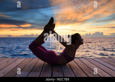 Les Maldives, South Ari Atoll, Thudufushi Island Resort Diamonds Thudufushi, femme, pratiquant le Yoga au coucher du soleil (MR) Banque D'Images