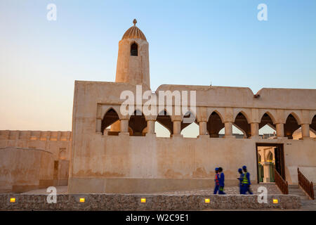 Qatar, Doha, Men Walking passé mosquée près de Fanar Qatar Centre culturel islamique Banque D'Images