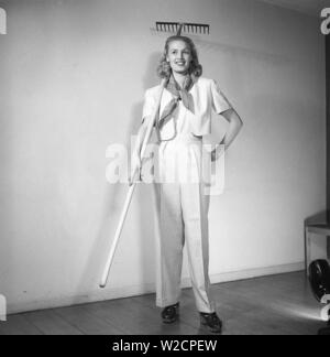 Tenue d'été 1940. Une jeune blonde femme porte une tenue d'été pratique depuis longtemps avec un pantalon blanc et une veste courte. En maintenant un râteau c'est laissé entendre qu'elle est habillée pour travaux de jardinage. La Suède 1947 Kristoffersson Z25-3 Banque D'Images