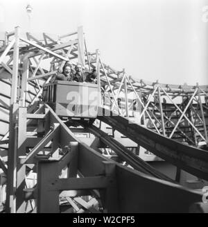 Parc d'attractions dans les années 1950 Parc d'attractions dans les années 1950 Qu'importe vieux ou jeune, monter dans les montagnes russes vous rend heureux. Photographié un groupe de personnes âgées qui montent dans les montagnes russes. Suède 1950. Kristoffersson réf. AY57-7 Banque D'Images