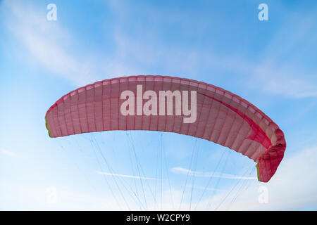 Vol en parapente de dome rose en bleu ciel clair Banque D'Images