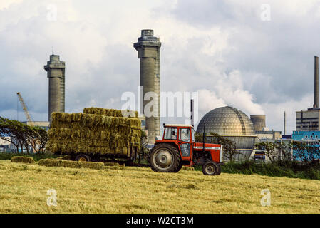 Sellafield, England, UK. Juillet 1986. L'usine de retraitement nucléaire. Un fermier recueilli ses bottes de foin devant le complexe industriel. Photo : © Simon Grosset. Archive : image numérisé à partir d'un original de la transparence. Banque D'Images