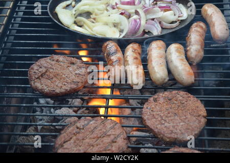 Saucisses et burgers de boeuf cuisson sur le barbecue Banque D'Images