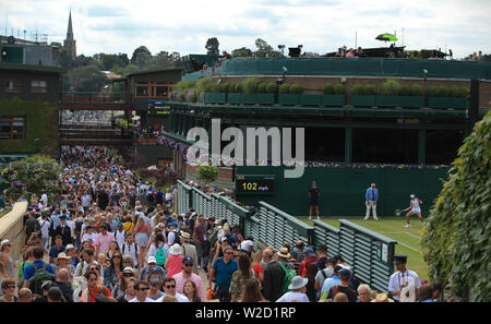 Les spectateurs font leur chemin cour passé dix-huit jours sur sept des championnats de Wimbledon à l'All England Lawn Tennis et croquet Club, Wimbledon. Banque D'Images