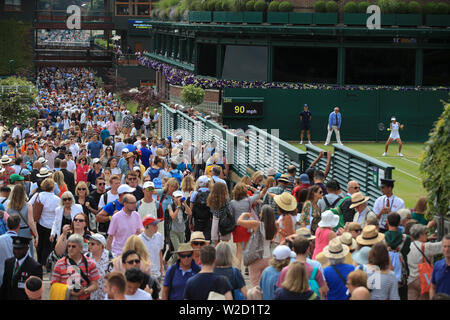 Les spectateurs font leur chemin cour passé dix-huit jours sur sept des championnats de Wimbledon à l'All England Lawn Tennis et croquet Club, Wimbledon. Banque D'Images