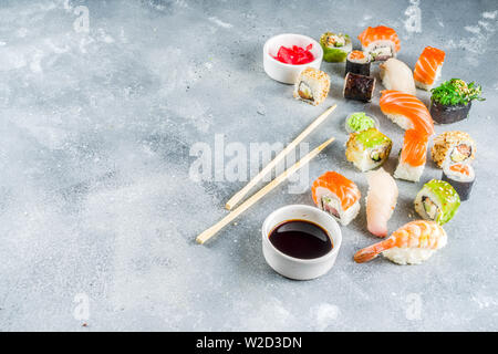 Assortiment de sushi situé sur la pierre ou le béton. Classique japonais sushi, nigiri sushi rolls., la sauce soja, le gingembre, de baguettes. Vue d'en haut. copy space Banque D'Images