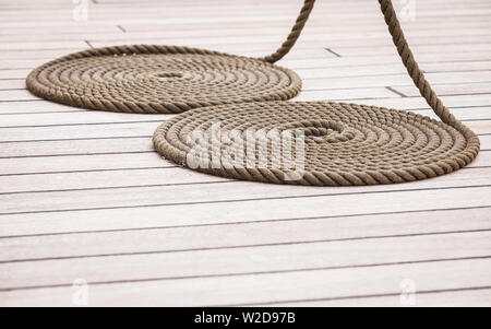 Vieux objets nautiques concept. Arrondi cercle commode ancienne bobine de corde sur plancher en bois. Banque D'Images