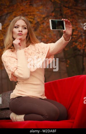 Photographie les gens concept. Jeune fille blonde en tenant un. selfies Belle femme prend photo avec téléphone mobile. Banque D'Images