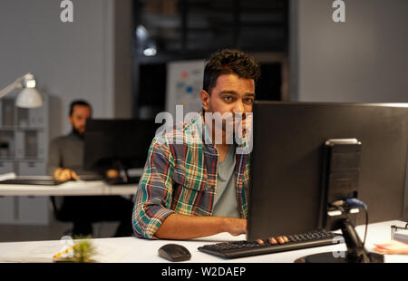 L'homme créatif avec l'ordinateur de bureau le travail de nuit Banque D'Images