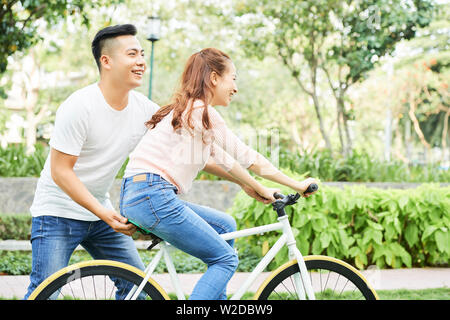 Asian young man holding le location et de l'enseignement sa petite amie de monter sur elle dans le parc Banque D'Images