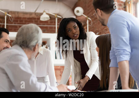 Femme sérieuse exécutif noir parler avec collègue masculin au briefing Banque D'Images
