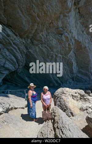 Deux touristes femmes posent près de l'entrée de la fameuse grotte naturelle dans Koba-Kaya sur Sentier de montagne Golitsyn, Novy Svet (Nouveau Monde), Crimée, Banque D'Images