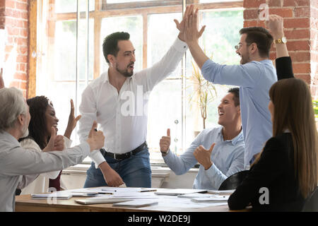 Heureux homme excité des collègues de donner une grande réunion du groupe à cinq Banque D'Images