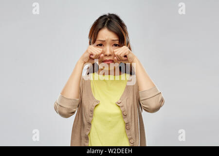 Femme asiatique triste pleurer sur fond gris Banque D'Images